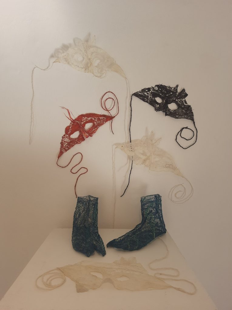 Display of tapa and lace masks and Hermes' boots